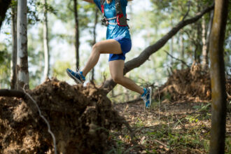 Sportswoman cross country trail running in forest
